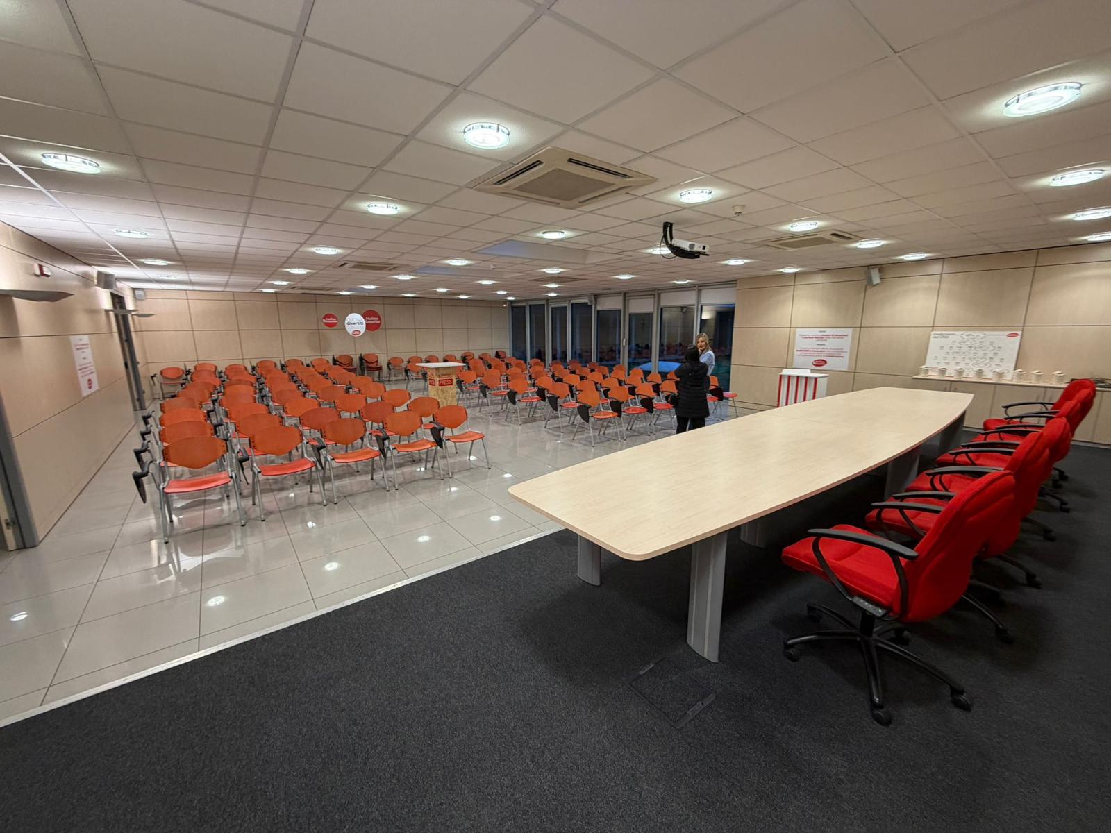 Sala conferenze con tavolo riunioni e sedute a platea